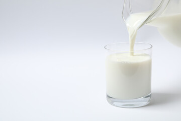 Pouring milk into glass on white background