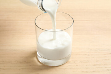 Pouring milk into glass on wooden table