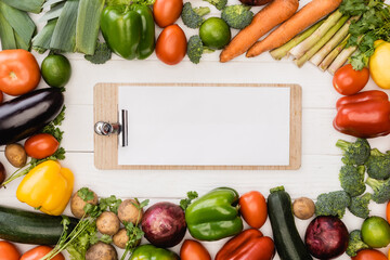 top view of fresh ripe vegetables and fruits near empty clipboard on wooden white background