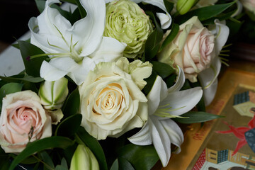 A bouquet of white roses with lilies are on the table