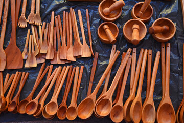 Many wooden spoons and wooden spatulas on black background on display