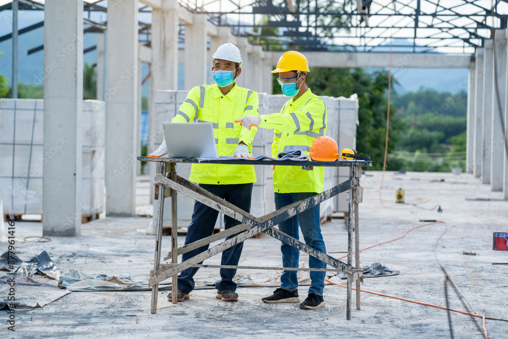 Aufkleber Architects and engineer wearing protective mask using laptop working about building structure on building site.