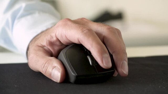 Slow motion close up shot of a hand working on a wireless mouse in a bright corporate office