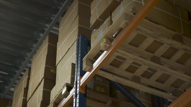 Cardboard boxed packages stacked up high in an industrial warehouse cinematic slow motion 4K