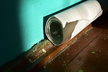 old roll of wallpaper on a dirty floor with cobwebs
