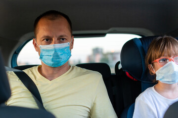 Fototapeta na wymiar happy male with daughter siting on rear seat with protective face mask in the car. 