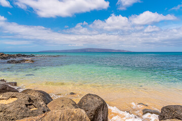 Fototapeta na wymiar Sandy beach with calm blue tropical water on sunny day