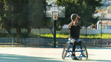 Young handsome man in wheelchair playing basketball