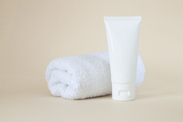 Fototapeta na wymiar Blank white cosmetic tube for cream, gel, cosmetic, medicine or toothpaste next to towel