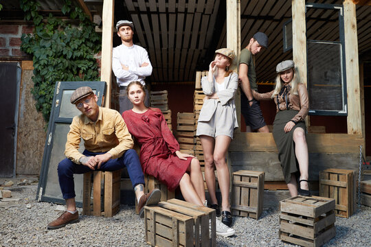 Group of young caucasian people,three girls and three men.They are siting on wooden boxes .