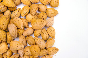 Inshell almonds on a white background. Almonds are arranged in a pile.