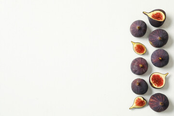 Whole and cut tasty fresh figs on white table, flat lay. Space for text