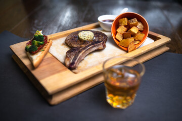 whiskey and steak on a wooden board. serving food in a restaurant