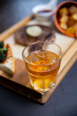 whiskey and steak on a wooden board. serving food in a restaurant