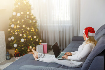 Happy woman looking in laptop in front of Christmas tree