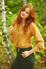 outdoor portrait of a beautiful redhead woman in autumn forest.