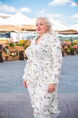 Plus size woman, American or European appearance walks in the city enjoying life. A young lady with excess weight, stylishly dressed in the center of the city. Natural beauty