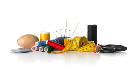 Collection of sewing tools with yarn, needles, scissors and tape measure on white background