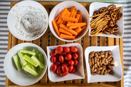 Assiettes garnies de tomates cocktail, biscuits, concombre et carottes, pour un ap&eacute;ritif. 
Une main d'enfant vient "picorer" dans une assiette.