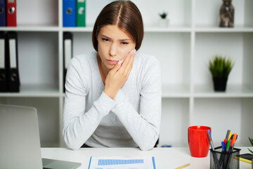 Beautiful young woman suffering from terrible severe toothache, touching cheek with hand.