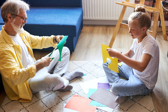 Helpful Senior Man Help Granddaughter To Do Homework, They Cut Out Cardboard Patterns