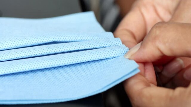 Sewing of protective masks against dirt, smog and virus, close-up view. Home production of face masks from sterilization paper.