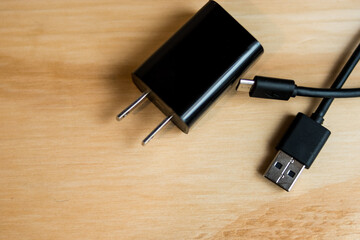 Black phone Charger and USB cable on a wooden table    