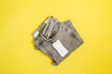 grey jeans with an empty tag on a yellow background