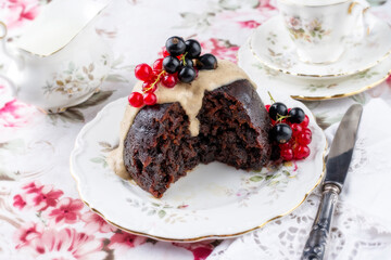 Traditional Australien plum pudding with vanilla rum sauce and fresh berries offered as closeup on a design plate