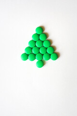 Christmas tree made of green pills or candy on white background. new year's card concept for medical field. mockup with copy space
