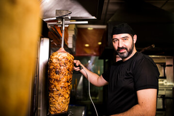 Bearded man preparing kebab meat in pizza bar.