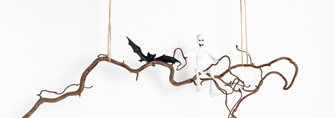 Minimal halloween decoration hanging on tree branch over white wall. Greeting card, holiday decoration concept. Copy space