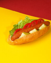 hot dog on yellow red background bun with sausage salad and cucumber
