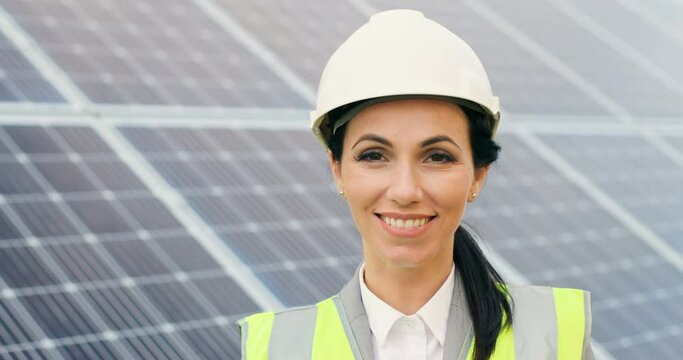 Close up portrait of young beautiful woman in protective helmet. Female engineer looking at camera and smiles.