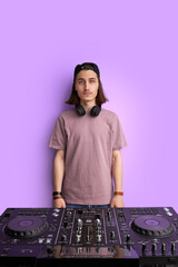 portrait of serious confident man in cap and headphones standing next to dj console, look at...
