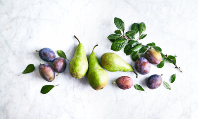 Autumnal fruits, plums and pears on stone background. Flat lay