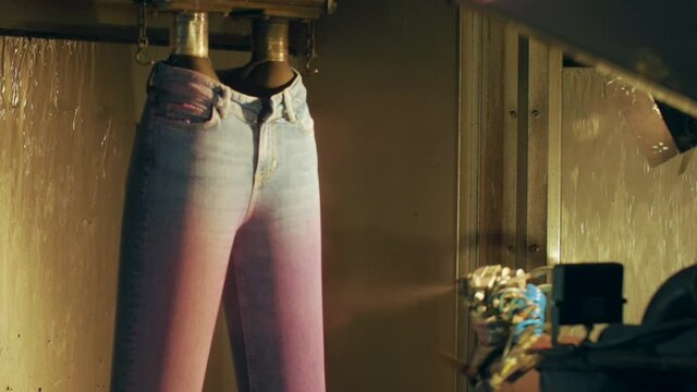 In the jeans factory, an industrial dyeing robot dyes jeans.