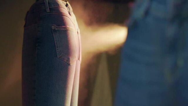 In the jeans factory, an industrial dyeing robot dyes jeans on inflatable models. the camera is focusing. there are smoke.