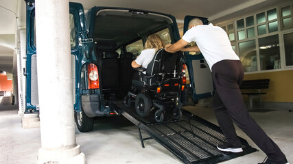 Wheelchair user leaving vehicle adapted for disabled transport with ramp and lift.