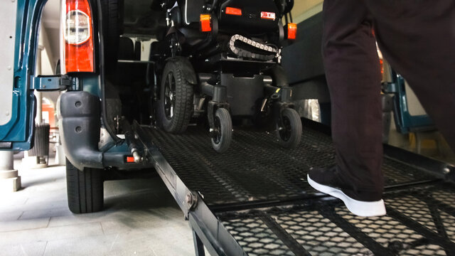 Wheelchair going into vehicle using ramp. Driver is helping to push it up.