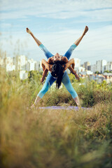 Two strong women doing acroyoga outdoors.