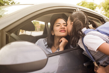 School girl kisses her mother before entering class. Young mother in the car, leaving her daughter...
