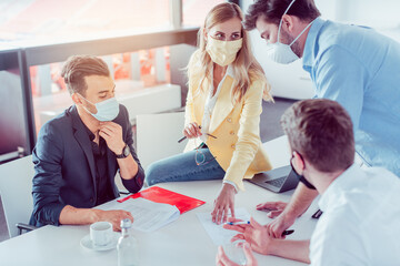 Team of business people with face masks during project meeting
