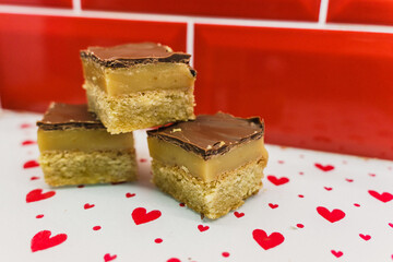 caramel shortbread traybake on heart platter with red background