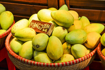 Wicker basket with ripe yellow mangoes and price tag. Ecologically clean exotic fruits. Local market for agricultural products.