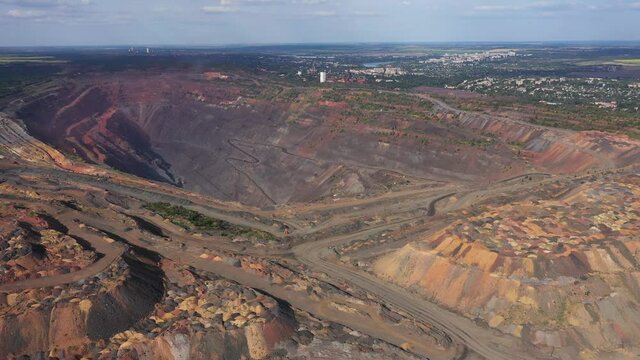 Large industrial open quarry with heavy transport equipment aerial panoramic view.