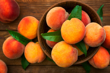 Ripe and tasty and juicy peaches lie on a plate on a wooden table. Large peaches on rustic wooden background, selective focus