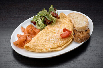 Omelet with salmon, herbs and ciabatta toast, on a dark background