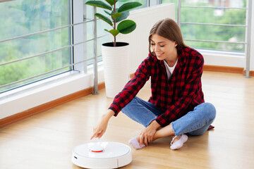 Woman turns on smart robot vacuum cleaner.