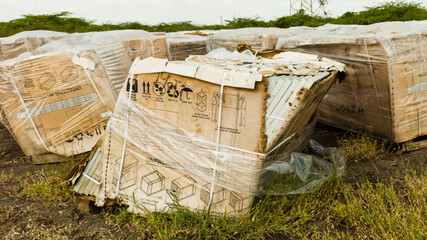 Damaged or broken photovoltaic solar panel / module pallets, stacked outside in abandoned condition.